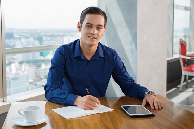 Smiling Businessman Making Notes in Restaurant