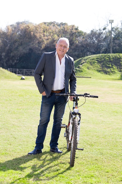 公園で彼の自転車とポーズ笑顔ビジネスマン