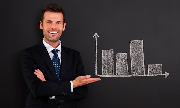 Smiling businessman presenting graph on blackboard