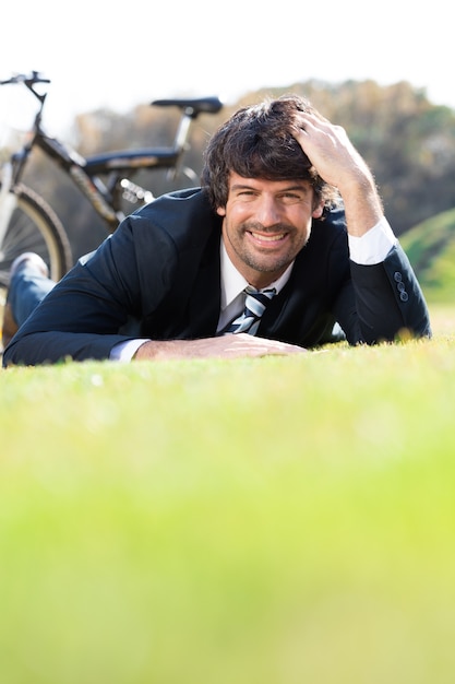 Free photo smiling businessman resting on the grass