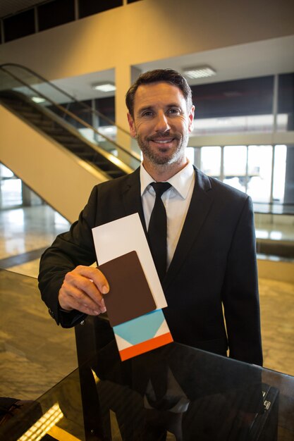 Smiling businessman showing his boarding pass