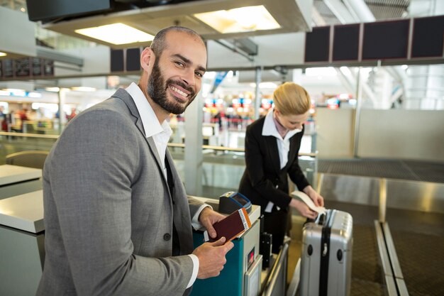 승무원 수하물에 태그를 고집하는 동안 여권으로 서 웃는 사업가