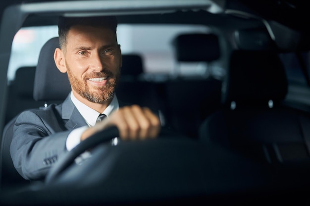 Foto gratuita uomo d'affari sorridente in vestito che esamina auto prima dell'acquisto