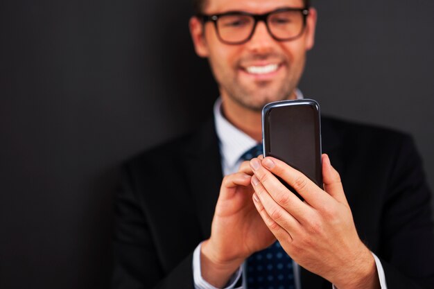 スマートフォンでビジネスマンのテキストメッセージを笑顔