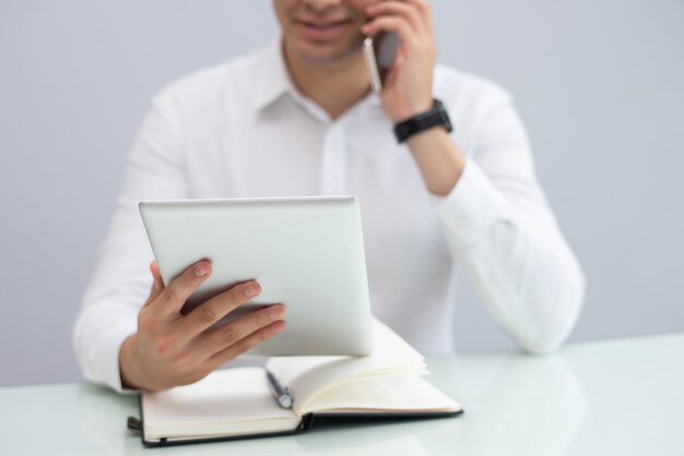 Smiling businessman using digital tablet and talking on phone