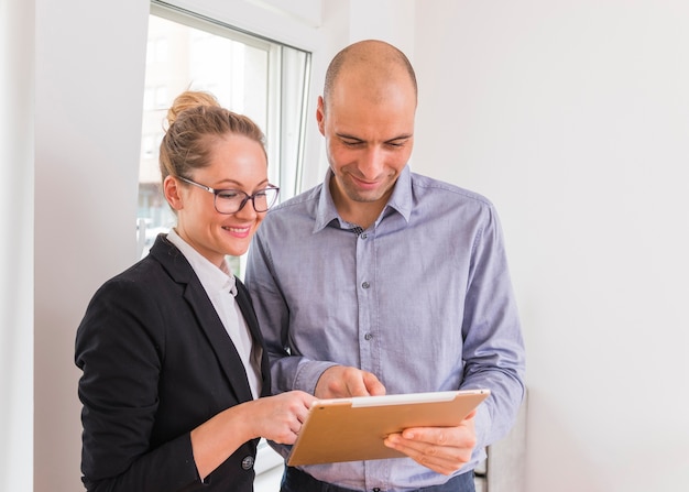 Free photo smiling businesswoman and businessman looking at digital tablet