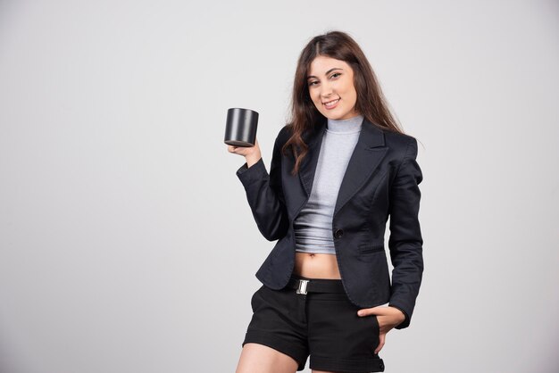 A smiling businesswoman holding a cup of coffee or tea . 