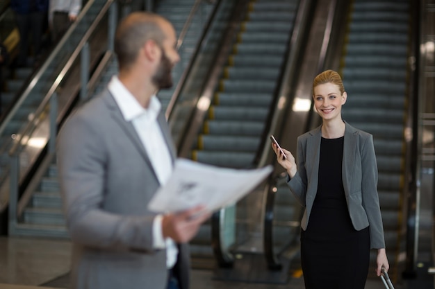 Smiling businesswoman interacting with businessman in waiting area