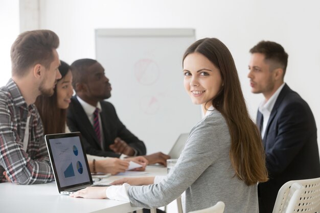Smiling businesswoman professional or intern looking at camera at meeting