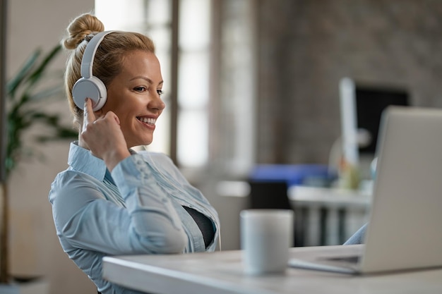 Smiling businesswoman relaxing with music over headphone while using computer in the office