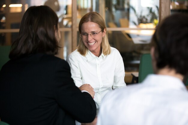 Smiling businesswoman shaking hand of businessman at negotiations or interview