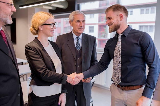 Smiling businesswoman shaking hand with businessman in the office