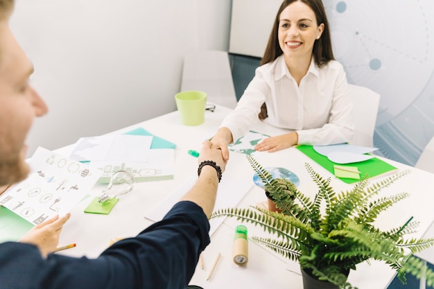 Foto gratuita donna di affari sorridente che stringe le mani con il suo collega in ufficio