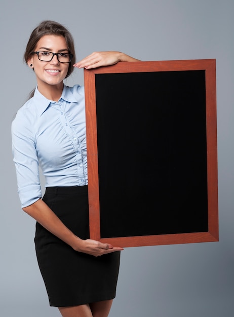 Free photo smiling businesswoman showing the empty blackboard