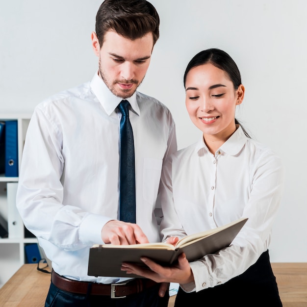 Smiling businesswoman showing something to her manager in diary