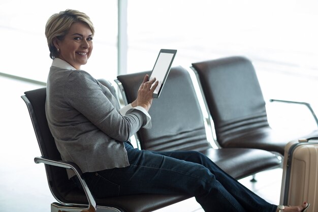 Smiling businesswoman using digital tablet in waiting area