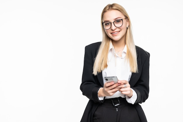 Smiling businesswoman using smartphone over gray wall.