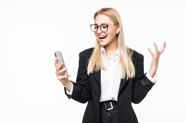 Smiling businesswoman using smartphone over gray wall.