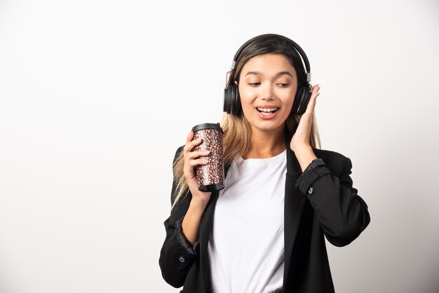 Smiling businesswoman with cup and headphones . 