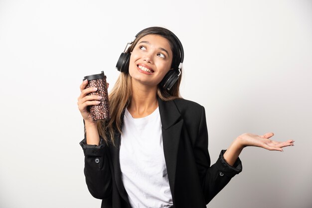 Smiling businesswoman with cup and headphones . 