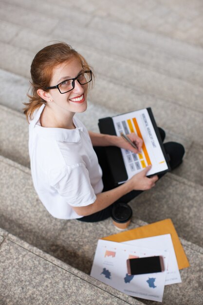 Smiling businesswoman with documents on stairs