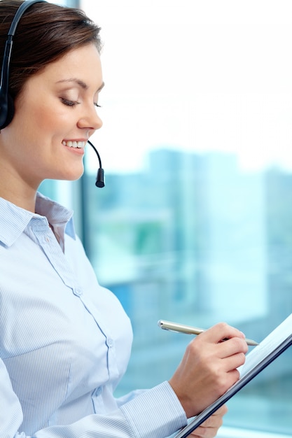 Smiling businesswoman writing on her clipboard