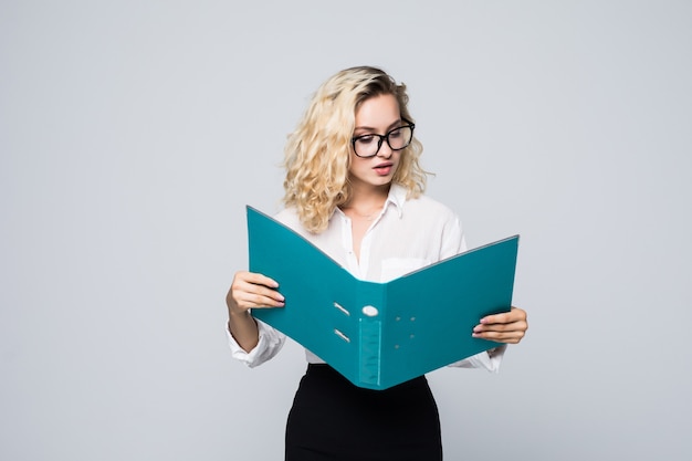 Smiling bussiness woman reading contracts from a folder isolated on white wall