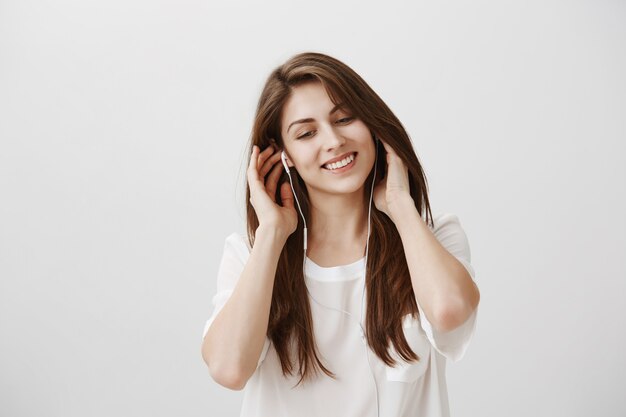 Smiling carefree woman listening music in earphones