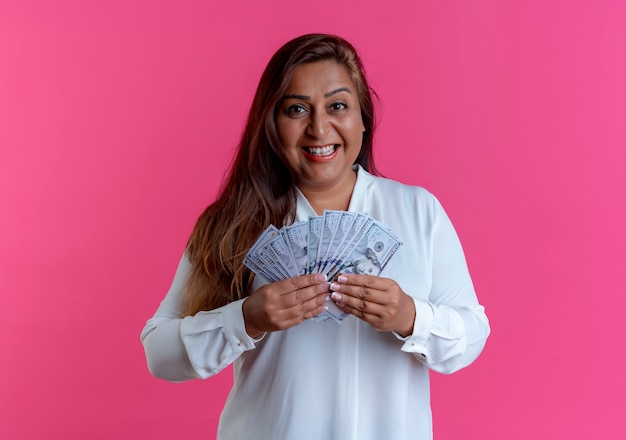 Smiling casual caucasian middle-aged woman holding cash on pink