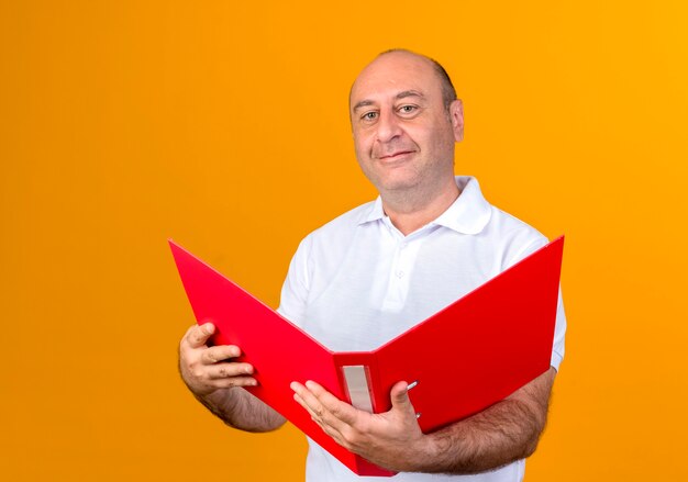 Smiling casual mature man holding folder isolated on yellow wall