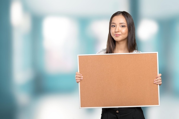 Smiling casual woman holding the empty corkboard