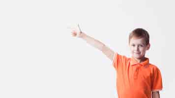 Free photo smiling caucasian boy pointing index finger at side on white backdrop