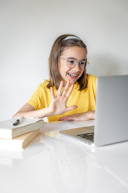 Sorridente ragazza caucasica che ha videochiamata in classe remota utilizzando il computer portatile