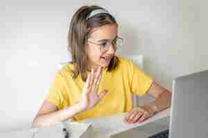 Free photo smiling caucasian girl having video call in remote classroom using laptop