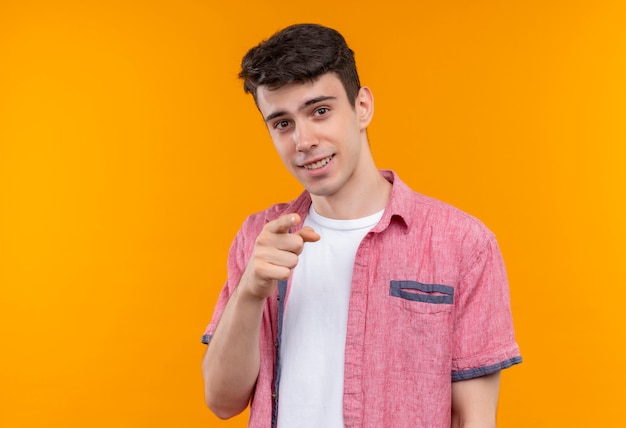 孤立したオレンジ色の背景にジェスチャーを示すピンクのシャツを着て笑顔の白人の若い男