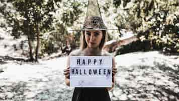 Free photo smiling charmer holding signboard in woods