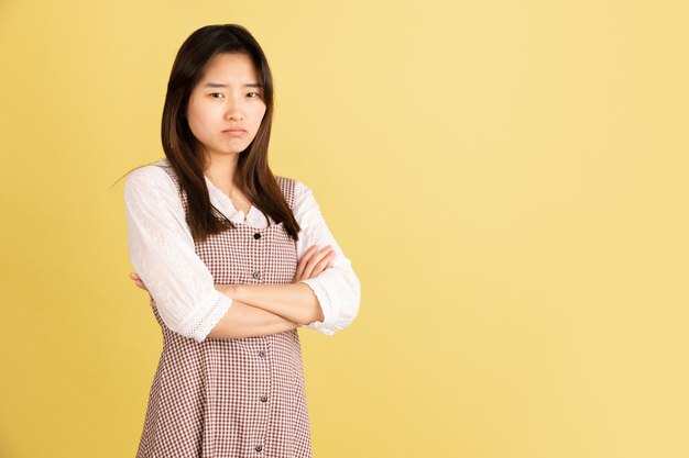 Smiling, cheerful. asian young woman's portrait on yellow  wall. beautiful female model in casual style. concept of human emotions, facial expression, youth, sales, ad.