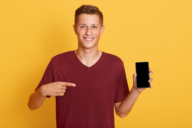 Free photo smiling cheerful guy holding phone with blank screen