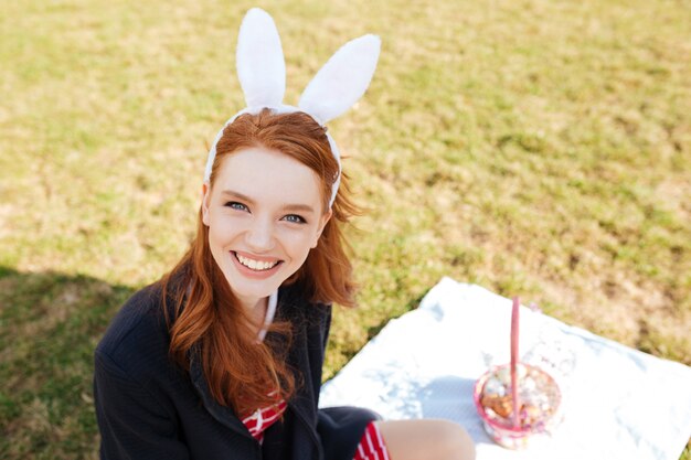 토끼 귀를 입고 긴 붉은 머리를 가진 웃는 쾌활 한 여자