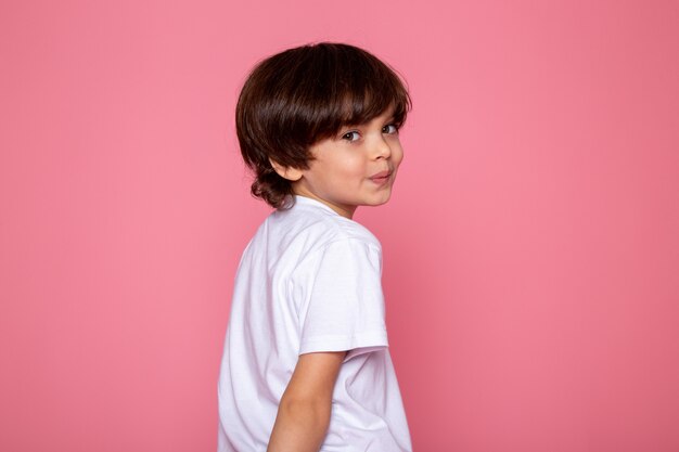 Smiling child boy little cute adorable in white t-shirt on pink desk