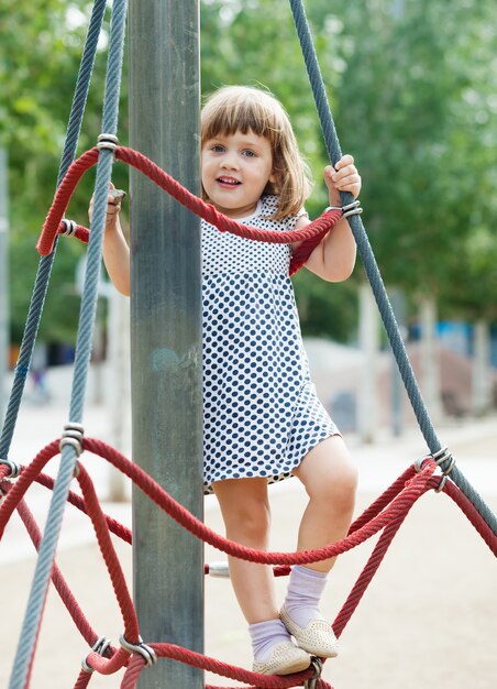 Smiling child climbing at ropes on playground
