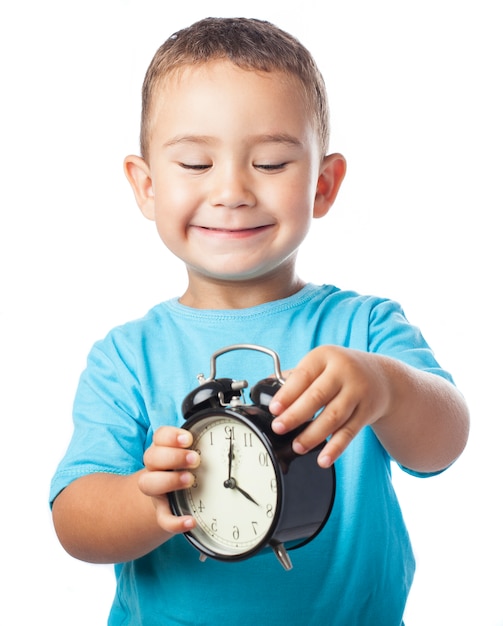 Smiling child playing with an alarm clock