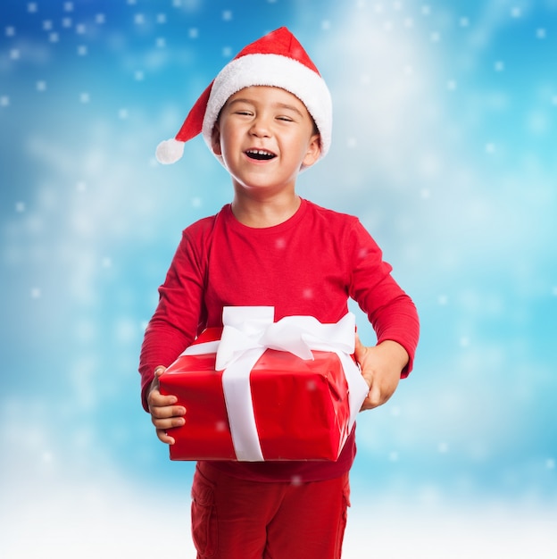 Улыбка ребенка с подарком и шляпу Санта Клауса