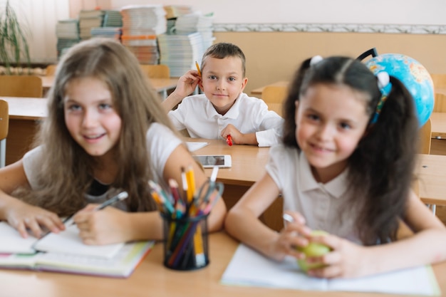 Smiling children sitting in classroom at desks. 