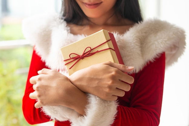 Улыбающаяся новогодняя девушка обнимает свой подарок