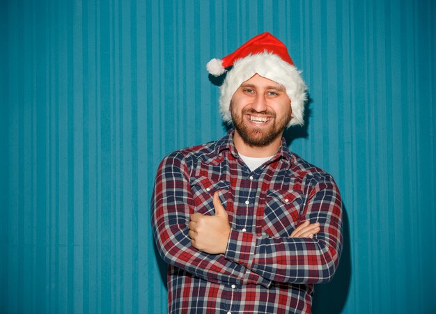 Smiling christmas man wearing a santa hat on the blue studio background