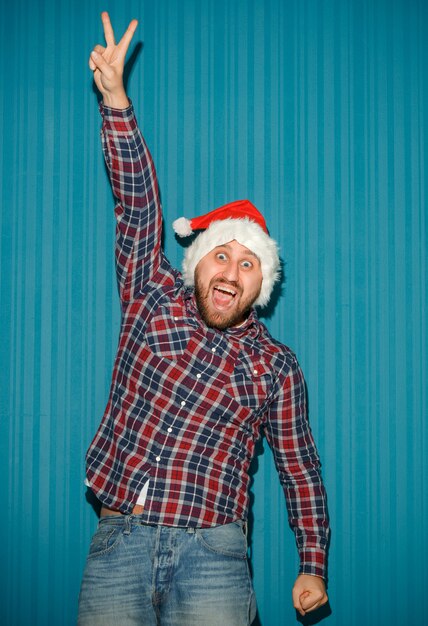 Улыбающийся рождественский мужчина в шляпе санта-клауса на синей студии