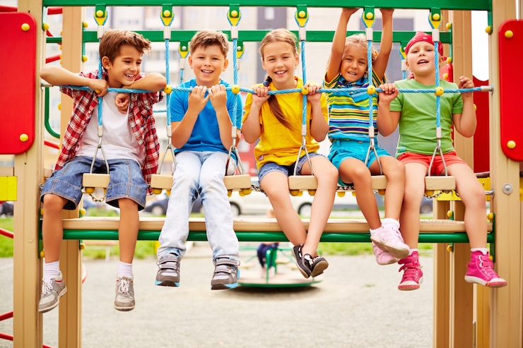 Free Photo smiling classmates sitting in a row on the playground