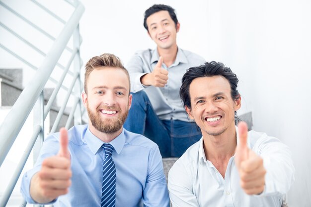 Smiling Colleagues Showing Thumbs up on Stairs