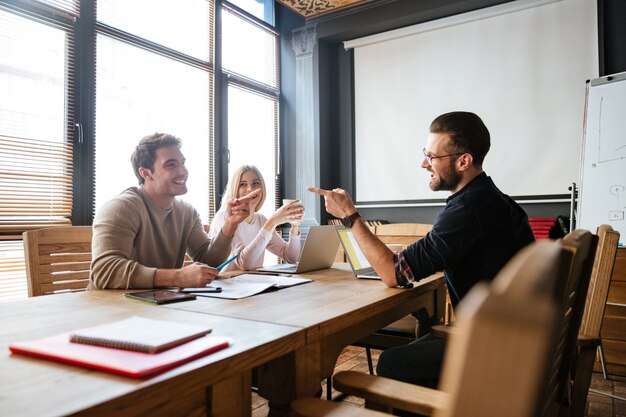 Smiling colleagues sitting near coffee while work with laptops